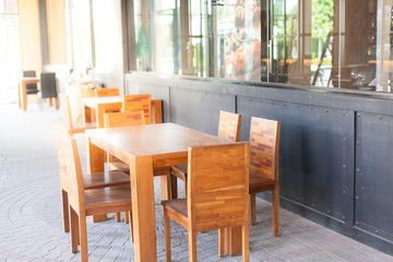 Outdoor wooden table and chair in front of restaurant. Soft focus and over lighting flares.