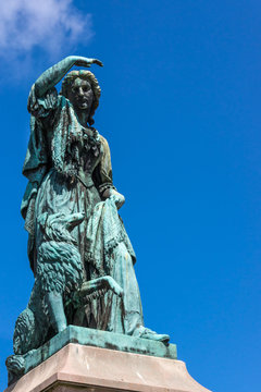 Inverness, Scotland - June 1, 2012: Closeup of greenish bronze Flora MacDonald statue shows the heroic lady and her dog against blue sky. No pedestal. 