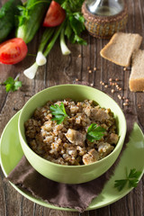 Buckwheat with meat stew and fresh vegetables on a wooden table.