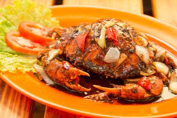Crab cooked with black pepper sauce on plate with chili and onion