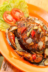 Crab cooked with black pepper sauce on plate with chili and onion
