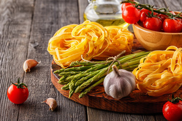 Products for cooking - fresh asparagus, pasta, olive oil.