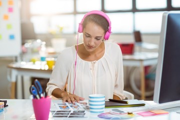 Fototapeta premium Graphic designer listening to music and looking at color swatch