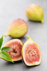 Whole figs and one fig sliced in half on top of a gray table.