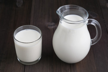 Obraz na płótnie Canvas full jug and glass with milk on wooden background