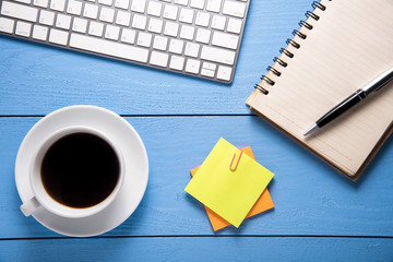 Wood table with office supplies and cup of coffee, top view