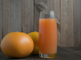 two grapefruits with glass of juice with wooden background