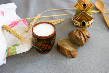 Bread,cup of milk,wheat spike,the clay mill on the gray fabric t