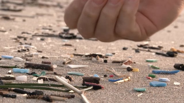 A helping hand picks up microplastic beach debris washed up from the Pacific Ocean at thr Oregon Coast.