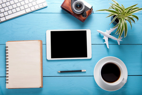 tablet on office table with notepad, computer and coffee cup, camera on blue wooden table background