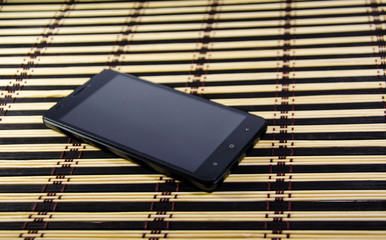 Black smartphone on a bamboo mat