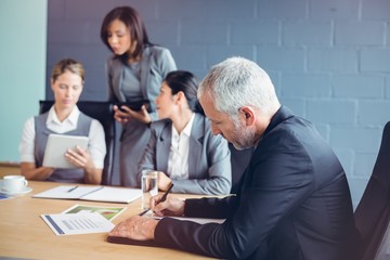 Businessman writing report in conference room