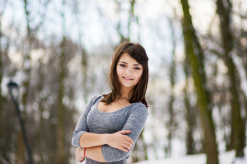 The girl with dark hair standing in a park and smiling