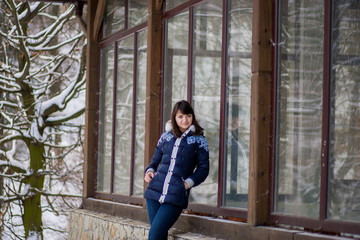 The girl stands near the house leaning on window