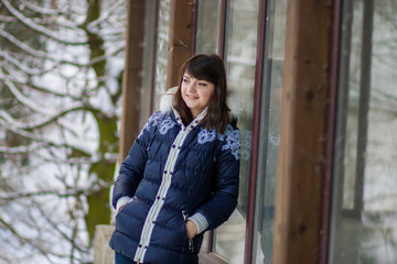 The girl stands near the house leaning on window