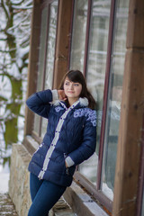 The girl stands near the house leaning on window