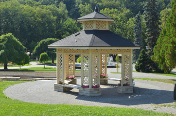 Elegant gazebo surrounded with lush park trees in summertime