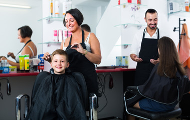 hairdresser cutting hair of boy
