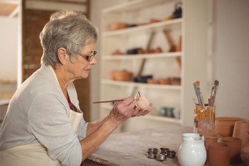 Female potter painting on bowl
