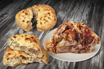 Spit Roasted Juicy Pork Ham With Two Pitta Bread Torn Loafs In Half Set On Old Cracked Flaky Wooden Garden Table