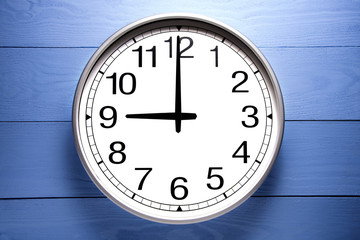 Fototapeta na wymiar Round clock shows shows at 9 o'clock, clock on blue background