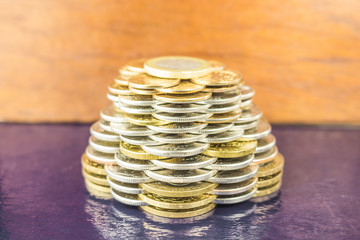 The pyramids of gold and silver coins on brown blurred background. Business concept finance.