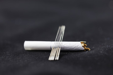Акупунктурные иглы лежат на сигарете.