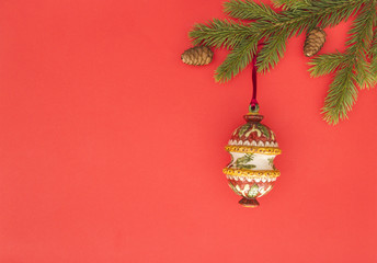 Christmas composition on red background. Green fir tree branches and Xmas decoration. Top view, flat lay. Copy space for text