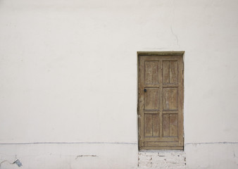 A wooden door on a white wall.