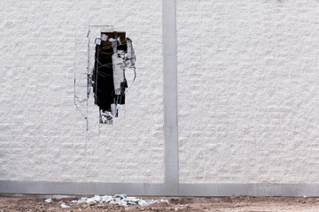 Brick wall being demolished with a big hole in it.