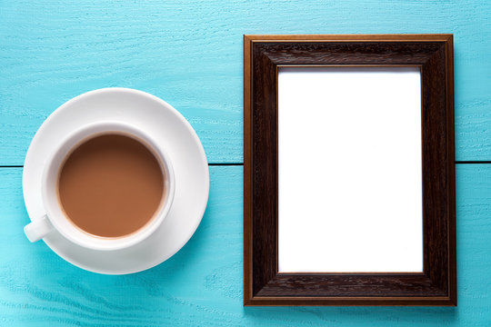 empty photo frames on wooden table with cup of tea. 