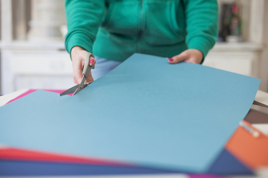 Young woman make scrapbook of the papers on the table using antique tools for cutting paper. Hand made photo album.Shallow depth of field