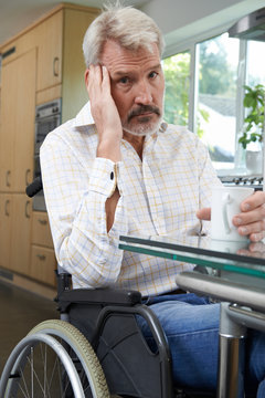 Depressed Man Sitting In Wheelchair At Home