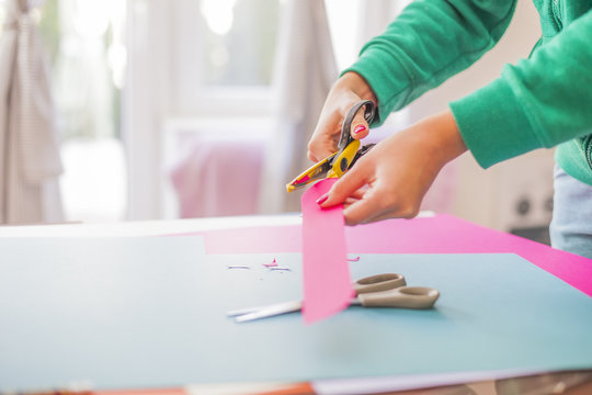 Young woman make scrapbook of the papers on the table using antique tools for cutting paper. Hand made photo album.Shallow depth of field
