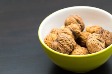 Walnuts in green ceramic bowl in close up.