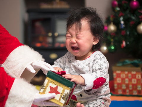 Santa claus bring a gift box to crying baby girl