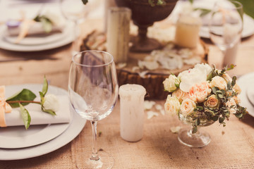 Table setting at wedding reception. Floral composition, candles and plates on decorated table.
