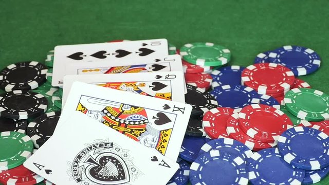 Hand throws flash royal playing cards on pile of red, green, blue and black casino chips, ace, king, queen, jack and dime of spades and of hearts, different angle, gambling. Close up, slow motion.