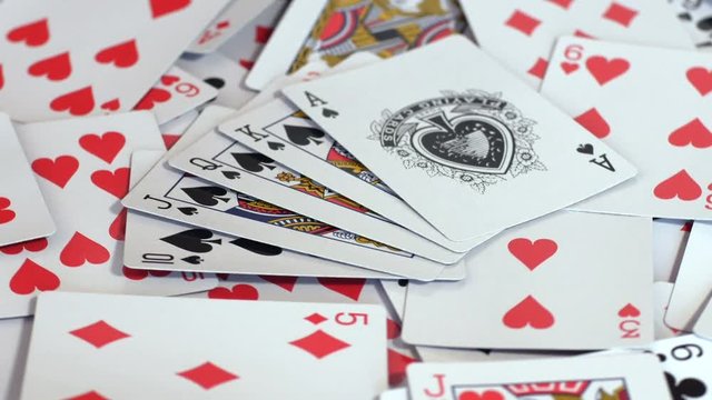 Ace, king, queen, jack and dime of spades royal flash rotating on pile of poker cards of different suits, hearts, diamonds, clubs, gambling. Close up, seamless loop, 4K Ultra HD.
