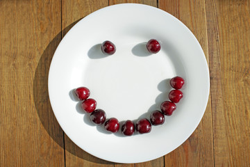 red cherries in shape of smile on the white plate