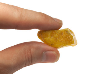 large piece of amber, between fingers on white background