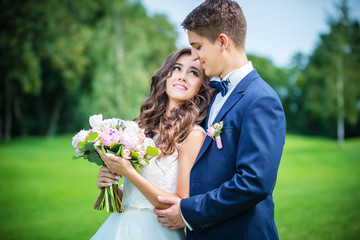 Beautiful young bride and groom going to kiss outdoors