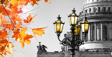 Black and white View of Saint Isaac Cathedral in Saint Petersburg with red and golden autumn leaves and shine vintage color street lamp. Autumn in St. Petersburg, Russia