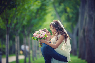 Beautiful young bride and groom going to kiss in park