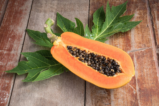 Ripe papaya with green leaf on wooden table.