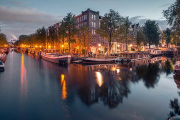 Fototapeta na wymiar Amsterdam canals and typical houses, boats and bicycles during evening twilight blue hour, Holland, Netherlands.