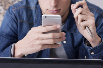 closeup of the hands with the mobile phone in the office with the laptop