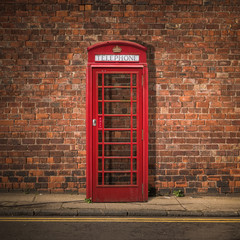 Fototapety  Brytyjska budka telefoniczna na ścianie z czerwonej cegły