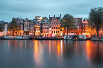 Fototapeta premium Amsterdam canal Amstel with typical dutch houses and boats during twilight blue hour, Holland, Netherlands.