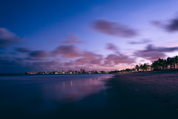 Obraz na płótnie Canvas Landscape photo of an urban beach after sunset with purple sky and sea
